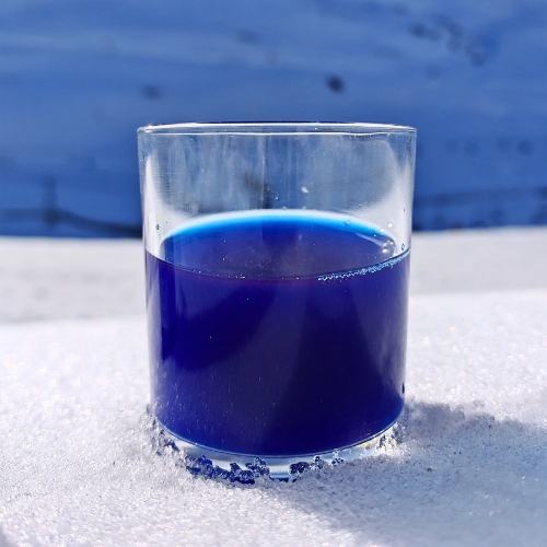 Image d'un verre de phycocyanine posé dans la neige